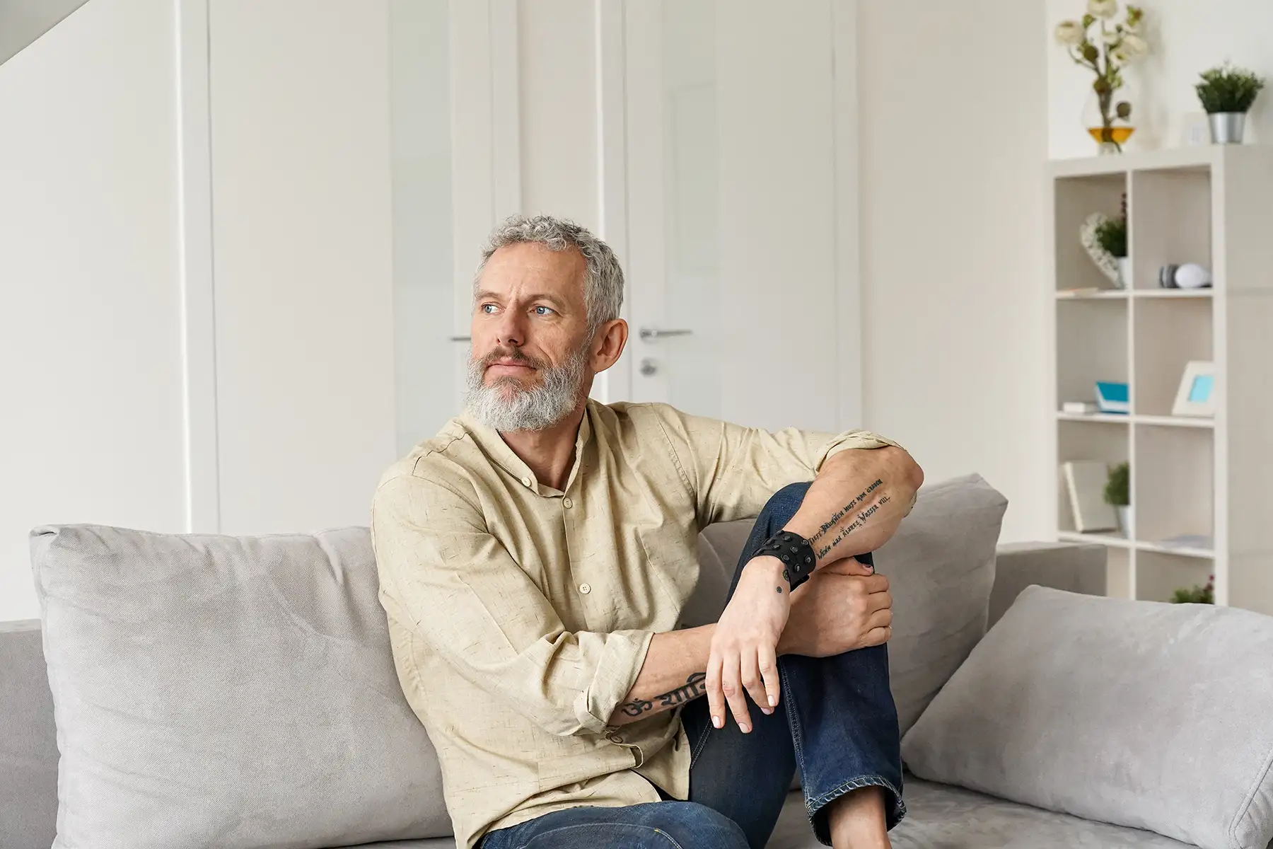 Middle aged man sitting on a sofa looking off into the distance